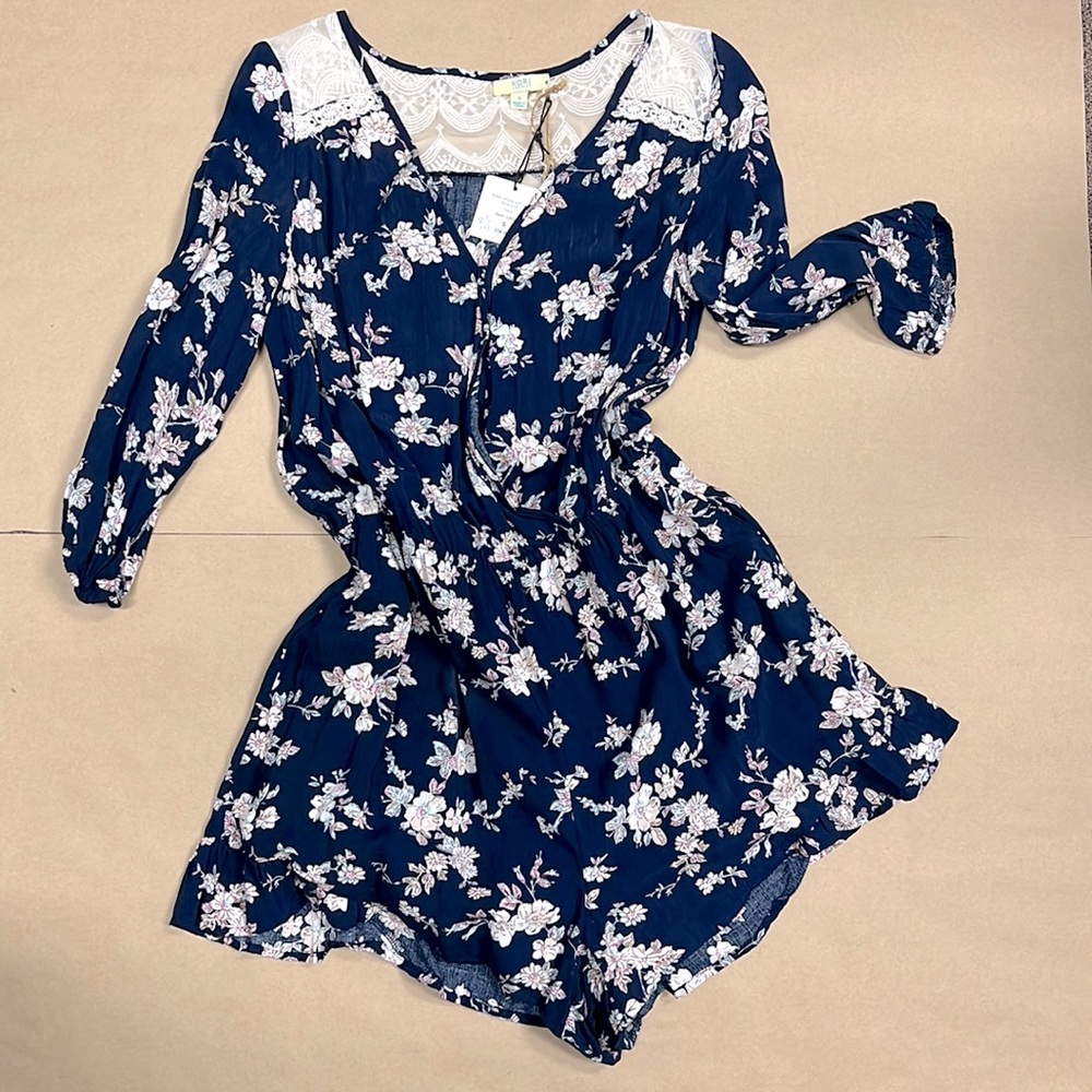 Navy ruffle romper with small floral print and lace yoke.